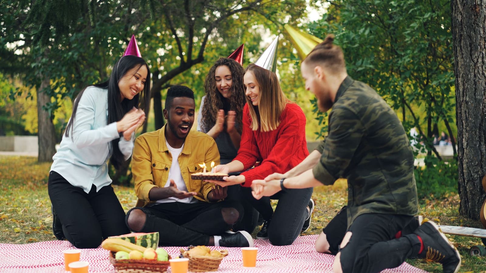 Groupe d'amis réunis en plein air autour d'un gâteau d'anniversaire