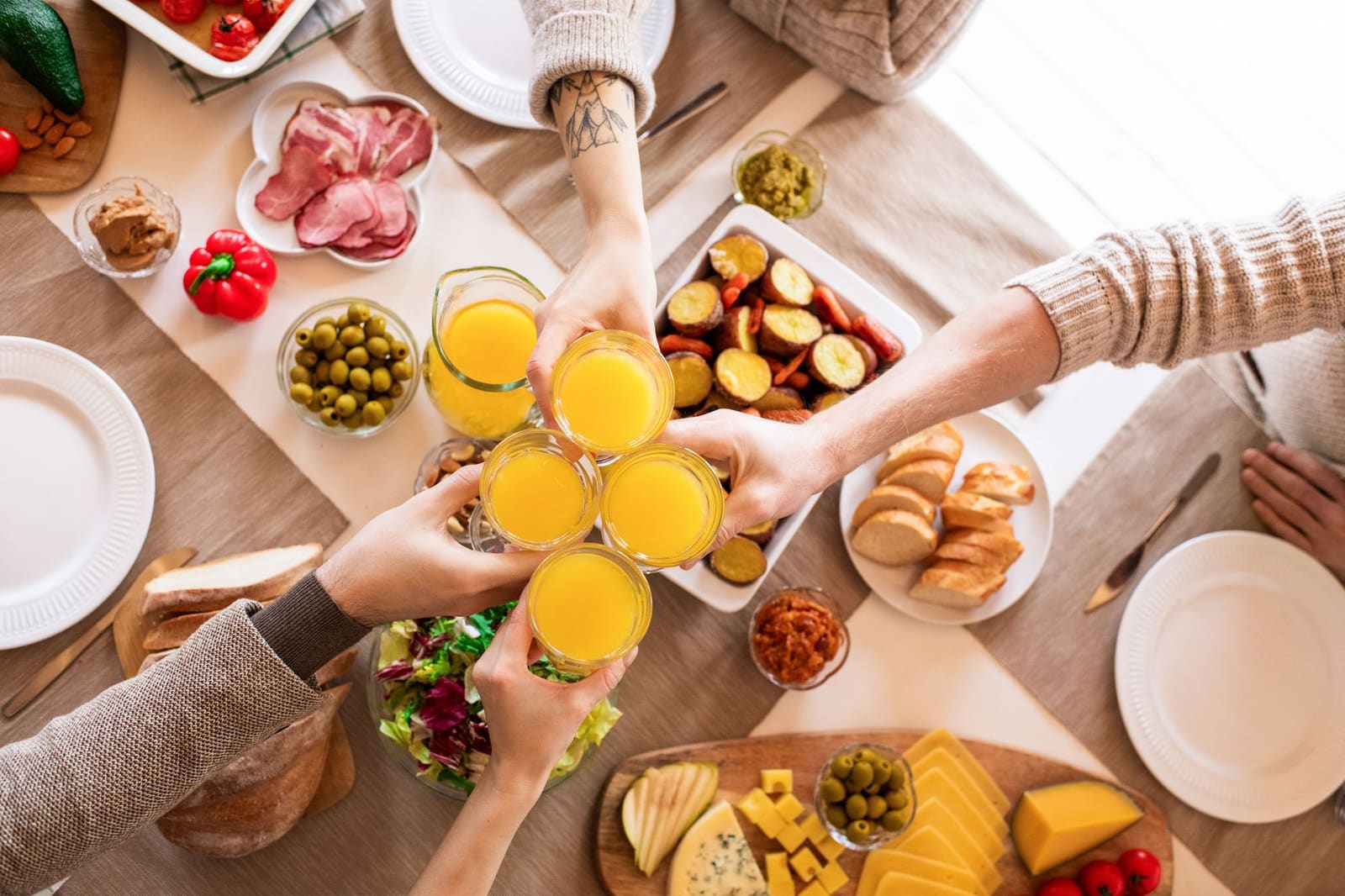 Amis trinquant au jus d'orange autour d'une table de brunch